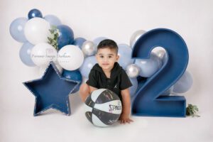Toddler boy with basketball beside large number two