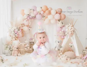 Baby in pastel birthday setup with balloons