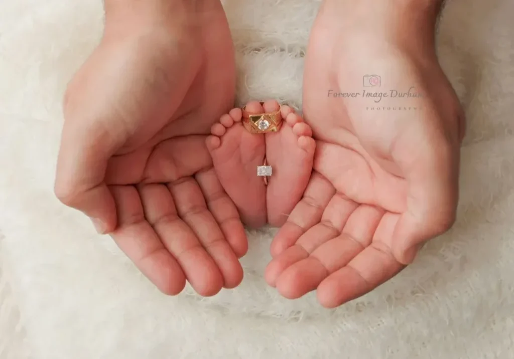 Baby feet in adult hands with rings